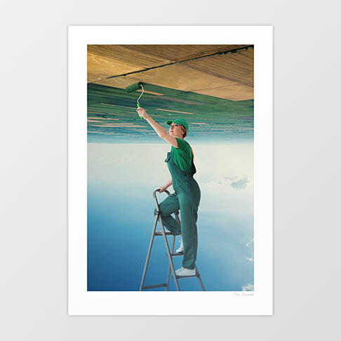 A Fresh Start surreal art print vertical — a woman in green dungarees cap and white trainers standing on a metal stepladder reaching upward with a paint roller applying vivid green paint to a burnt dry scorched brown landscape above her while open pale blue sky with cloud reflections fills the space below, surreal environmental renewal new beginnings climate hope art print for living rooms offices and eclectic interiors