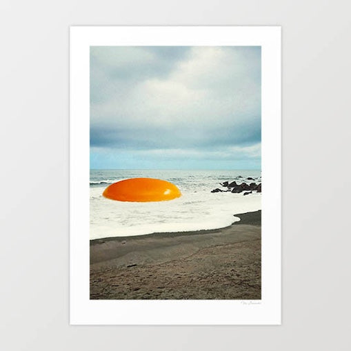 Giant golden egg yolk on sandy beach shoreline with ocean waves - surreal coastal food wall art print